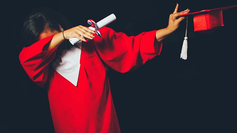 Person in red graduation gown holding certificate poses in front of black background