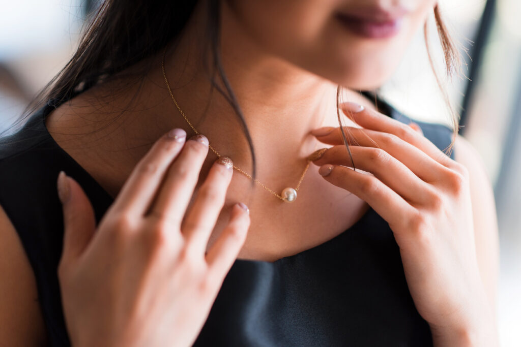 Young woman trying on neck an elegant pearl jewelry.Get dressed for the celebration