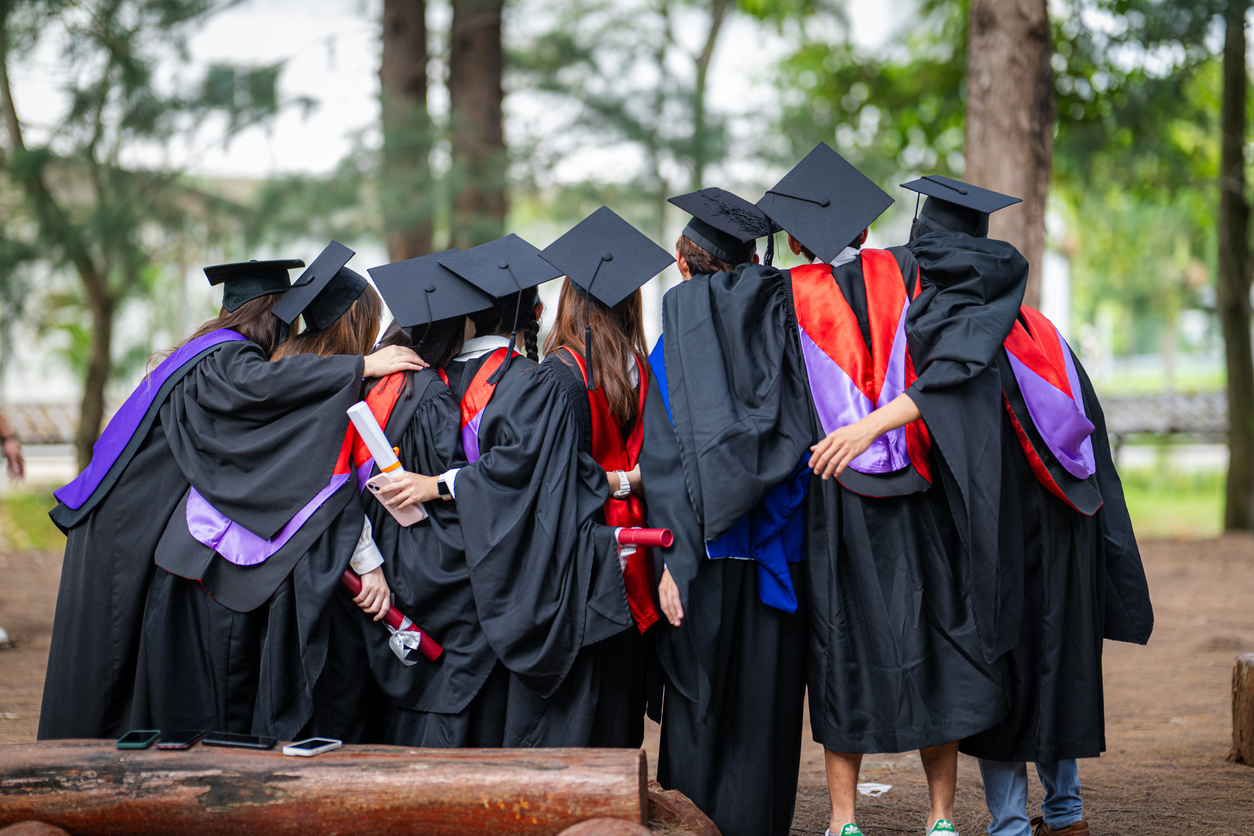 Rearview shot of a group of young students embracing on graduation day