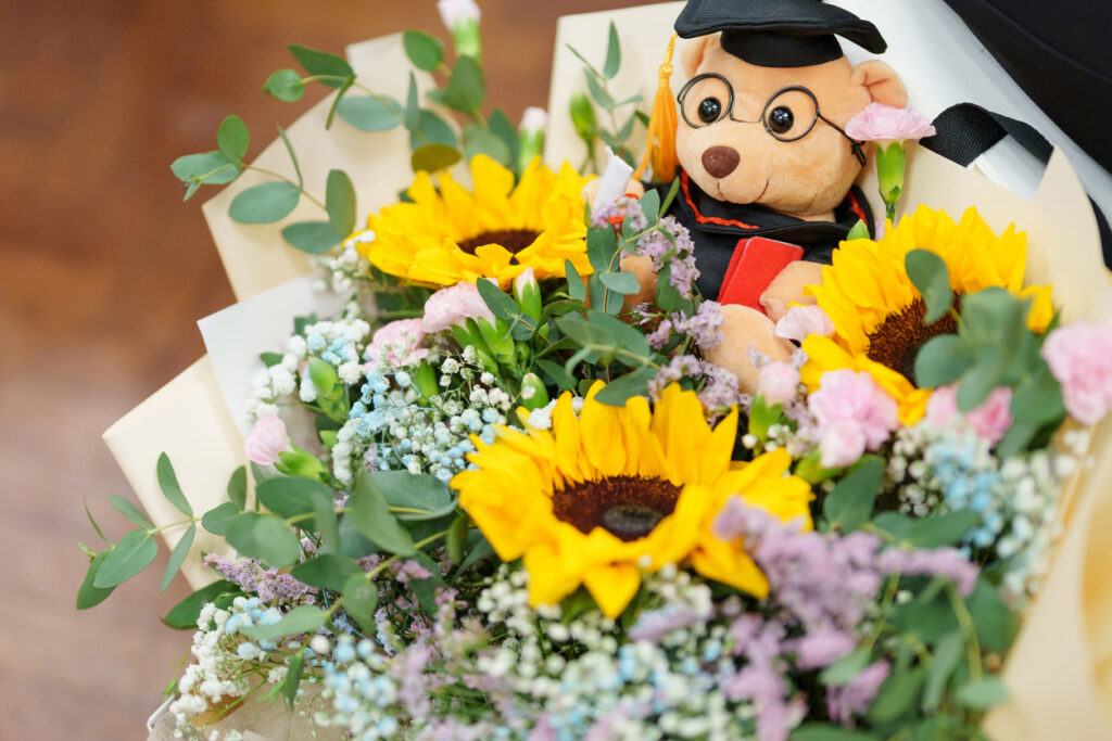 Close-up of a graduation flower bouquet with a cute soft toy bear.