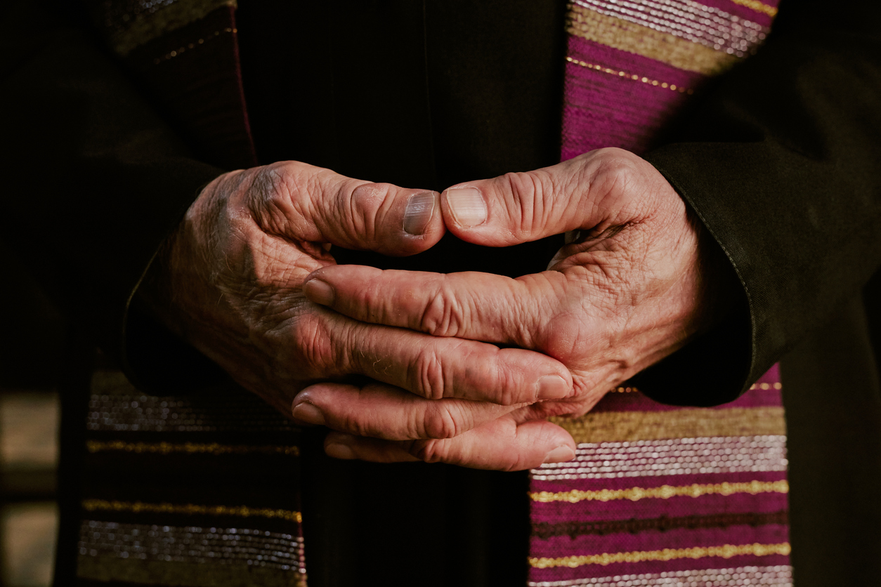 Medium close up of wrinkled unrecognizable male hands of priest