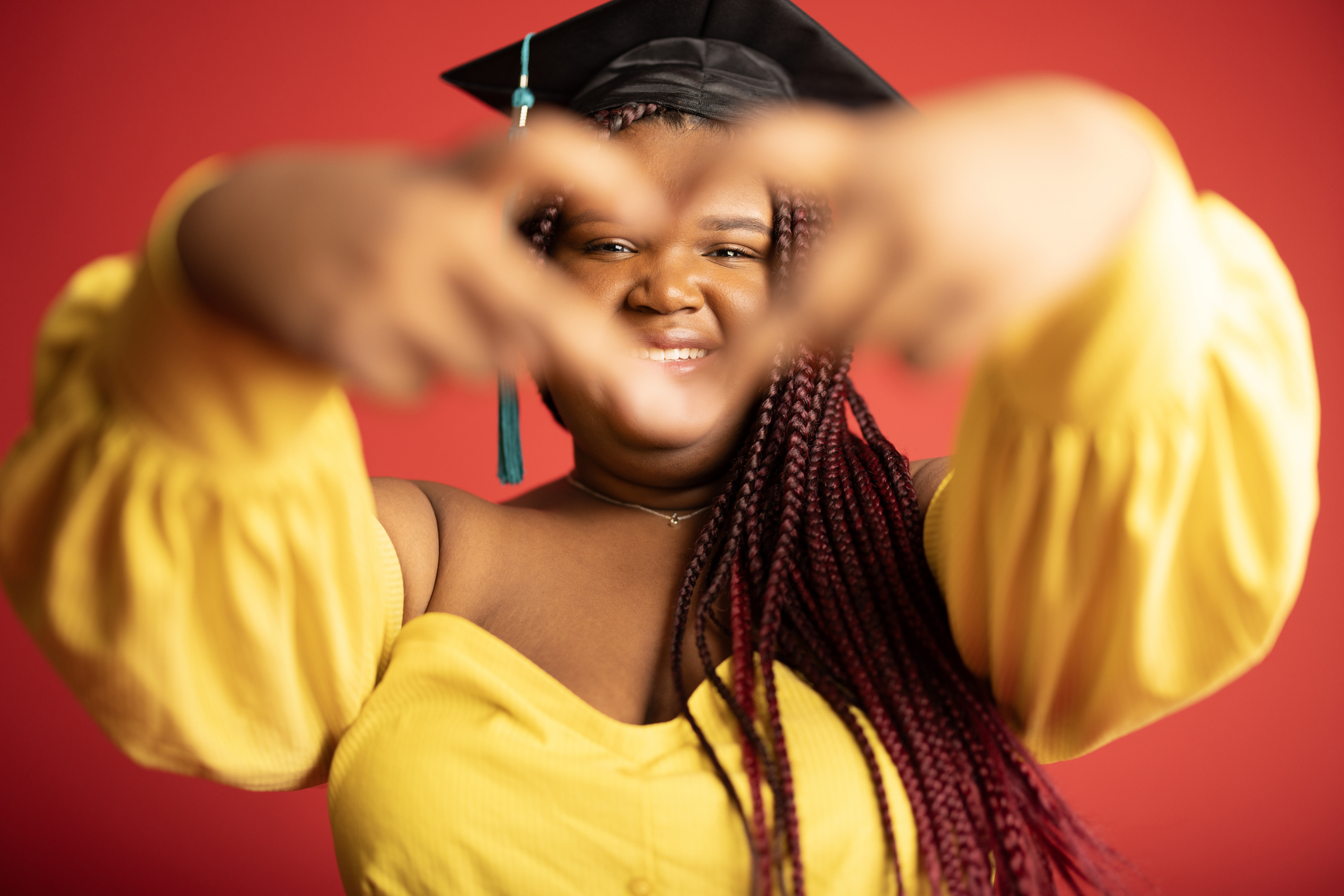 A young girl graduating from high school on a red background.